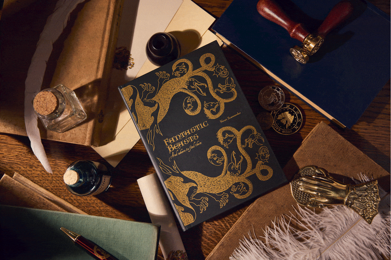 MinaLima designed textbooks on a wooden desktop, surrounded by quills, inks and stationery