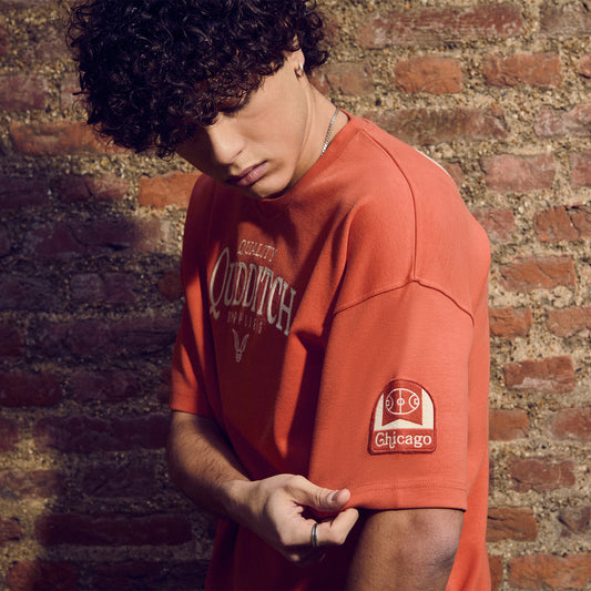 Person wearing a Quidditch t-shirt with a logo against a brick wall