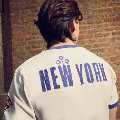 Person wearing a 'New York' Quidditch ringer t-shirt in front of a brick wall