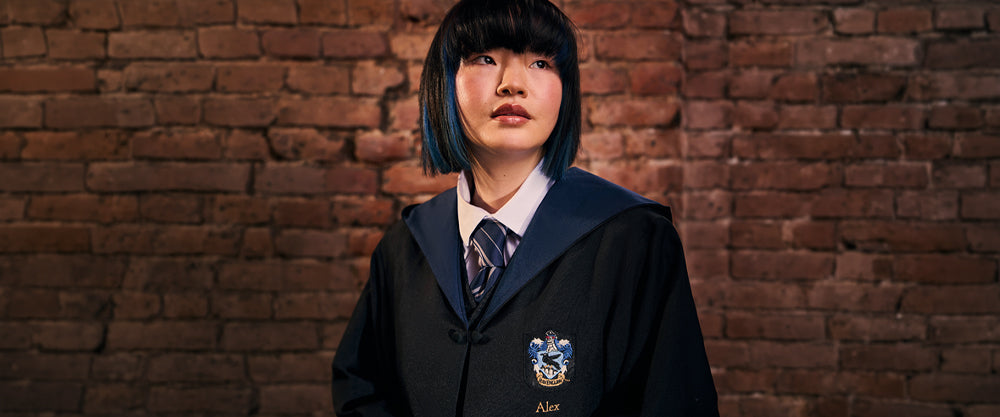Person wearing a Ravenclaw school uniform with a tie against a brick wall.