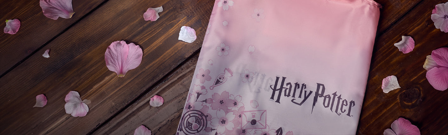 Pink 'Harry Potter' bag with sakura flower petals on a wooden surface