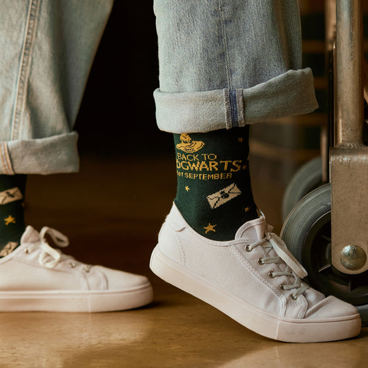 Person wearing a sock with 'Back to Hogwarts' text, standing next to a cart.