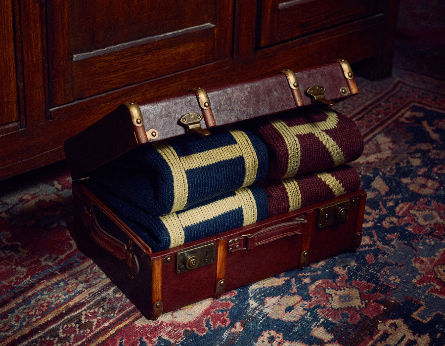 Harry Potter trunk half open, featuring 4 jumpers, 2 H for Harry Potter jumpers and 2 R for Ron Weasley jumpers. Trunk is on patterned carpet
